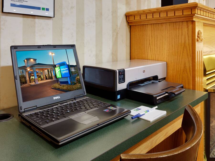 A hotel reception desk with a laptop, a printer, and a trash bin.