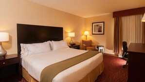 A hotel room with a large bed, two bedside tables with lamps, a chair, a desk, and a window with curtains. - Holiday Inn Express Vernon - Manchester by IHG (Vernon)