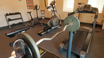 A gym with various exercise equipment including treadmills, stationary bikes, and free weights.
