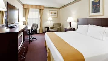 A hotel room with a bed, desk, chair, and a television.