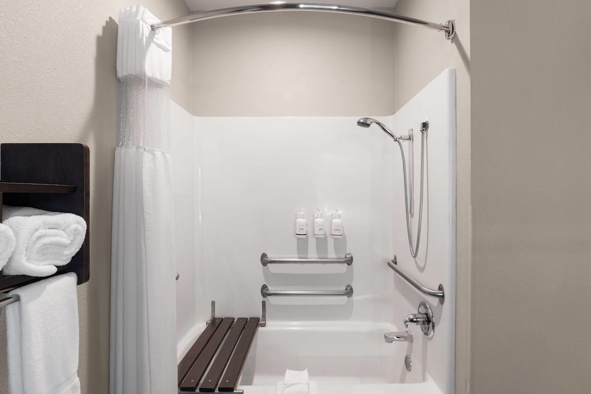 Un espace douche équipé d’une baignoire, d’un porte-serviettes et d’un pommeau de douche.