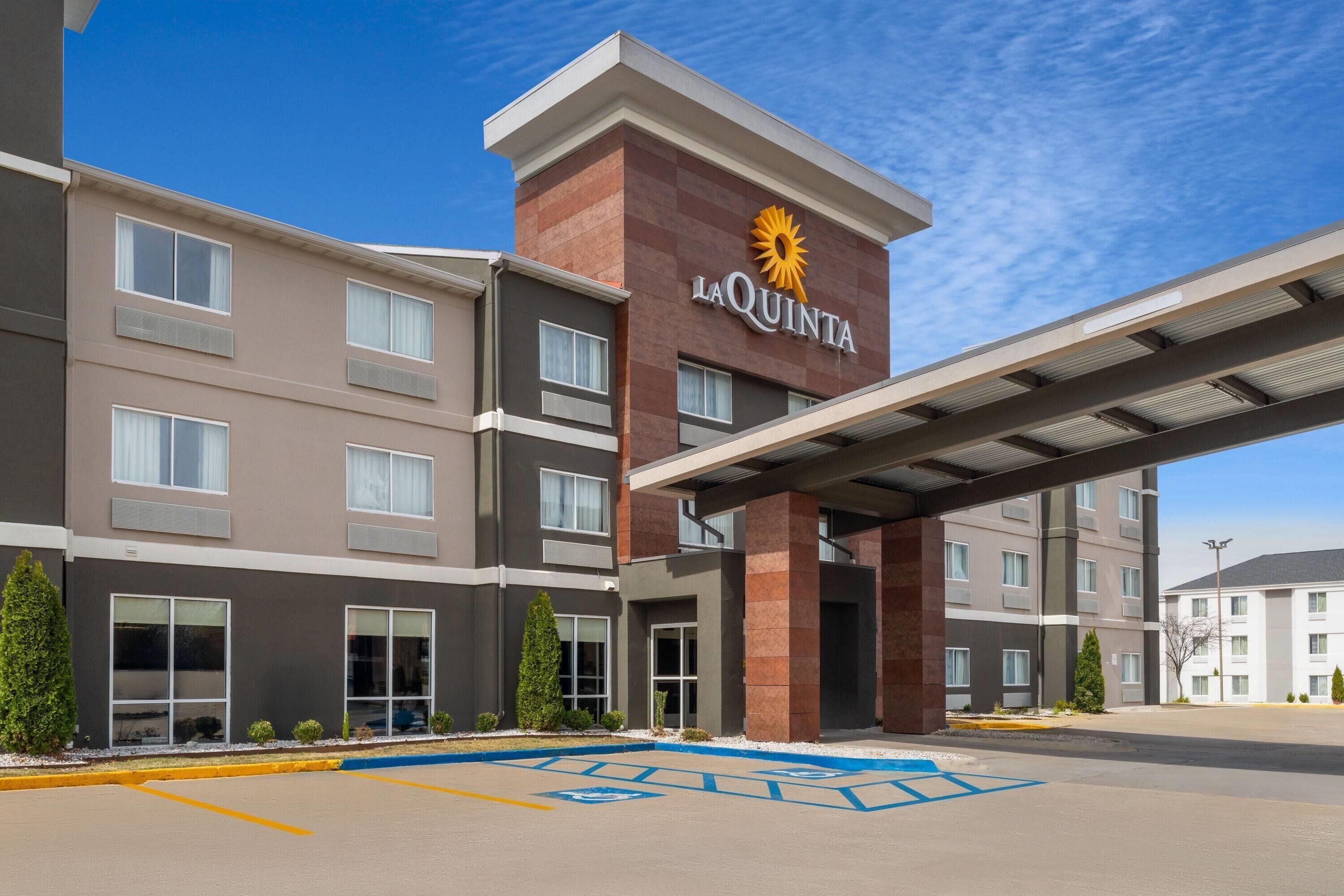 Een meerlaags hotel met een opvallend 'La Quinta'-bord, een overdekte ingang en een parkeerplaats met toegankelijkheid voor mindervaliden.