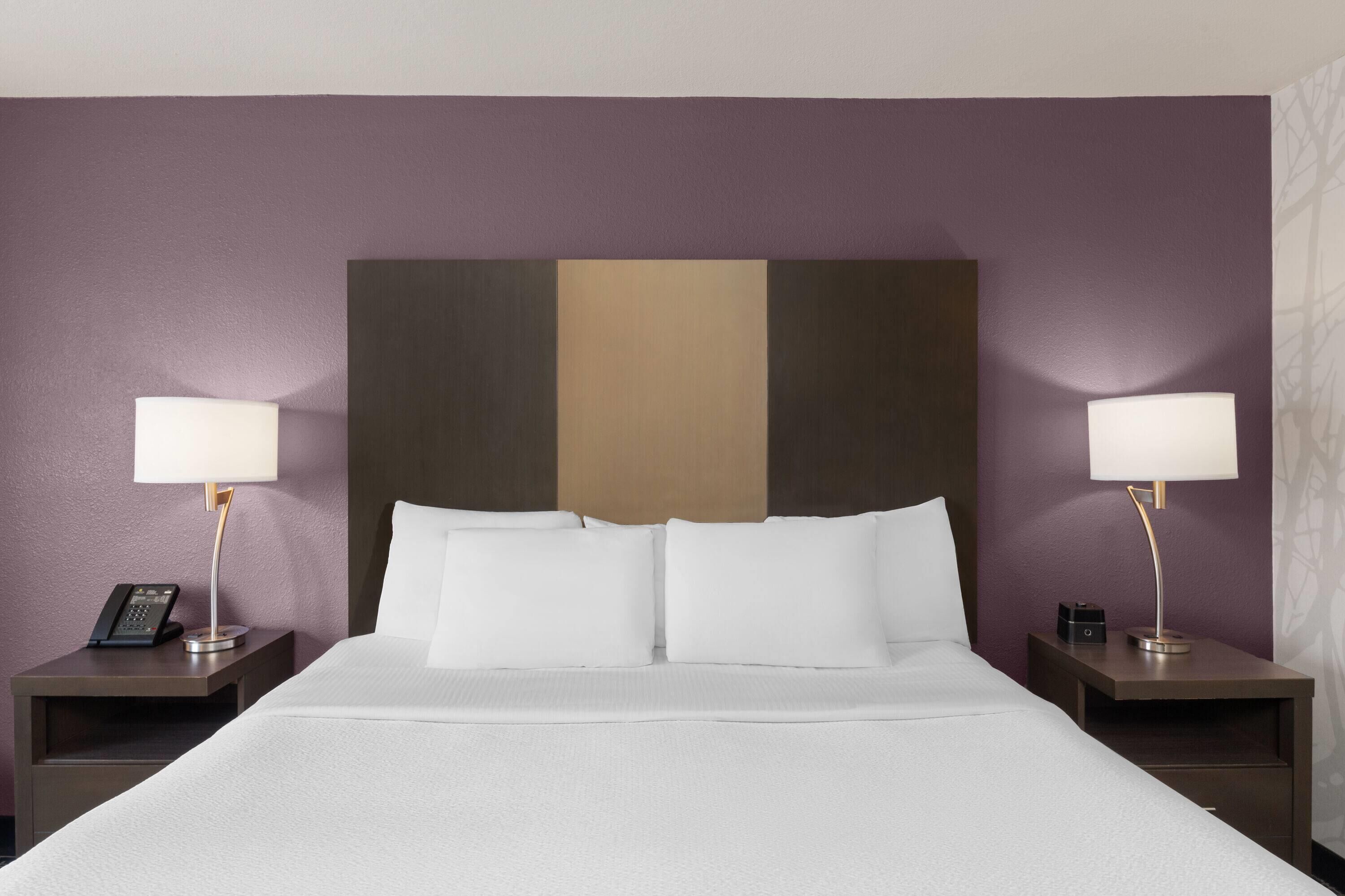 A hotel room with a bed, two bedside tables, lamps, and a telephone on one of the tables.