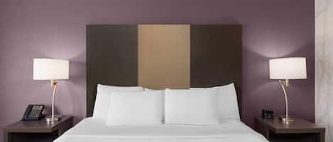 A hotel room with a bed, two bedside tables, lamps, and a telephone on one of the tables.