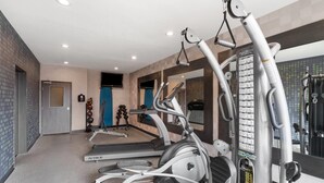 Une salle de sport équipée de tapis de course, de vélos elliptiques et de matériel de musculation.