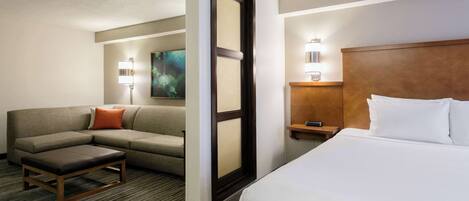 Una habitación de hotel con cama, sofá, una mesita y una lámpara en la mesilla.