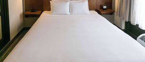 A hotel room with a large bed, two bedside tables, and two wall-mounted lamps.