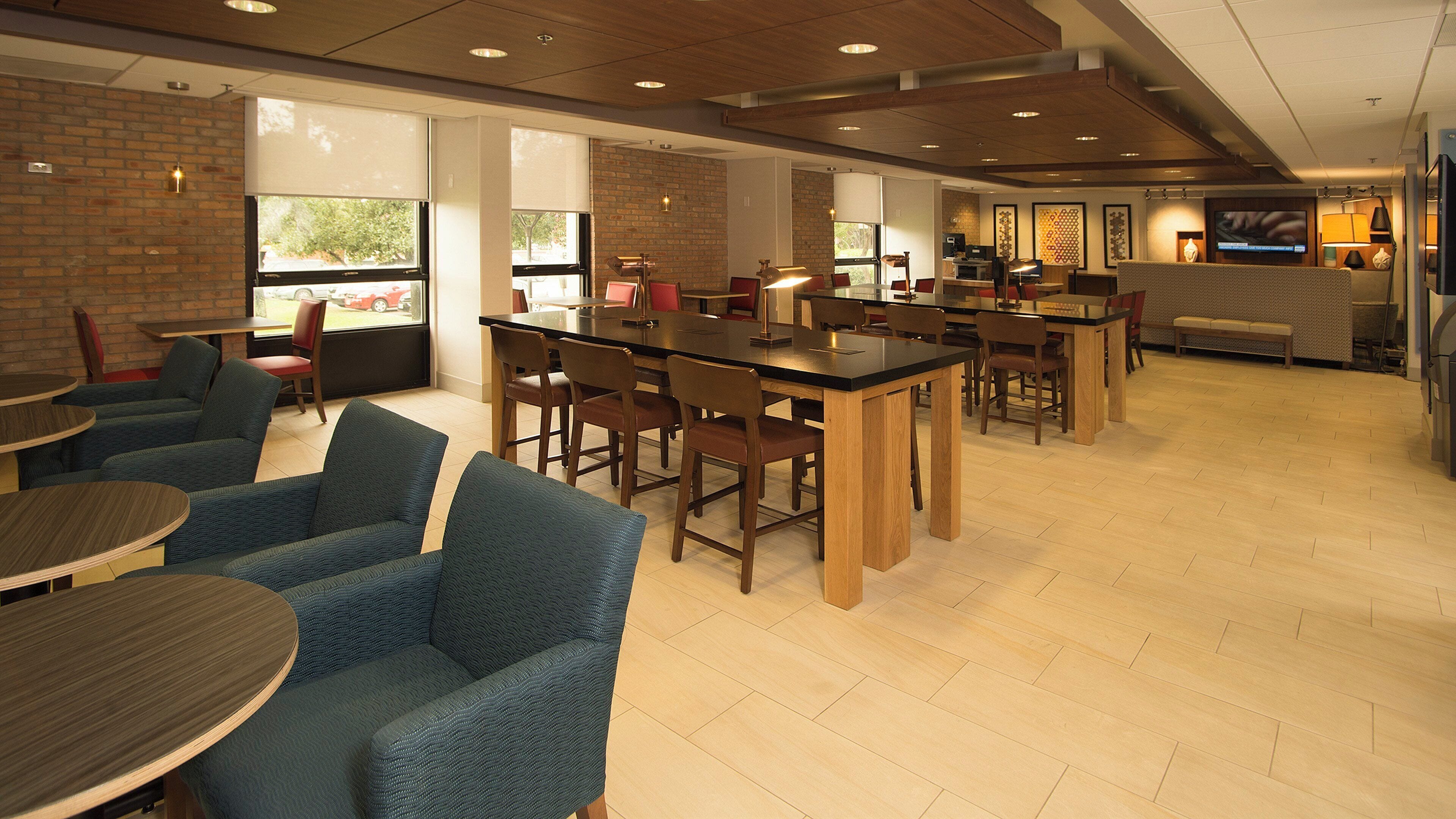 A modern hotel lobby with a bar area, seating arrangements, and a television screen.