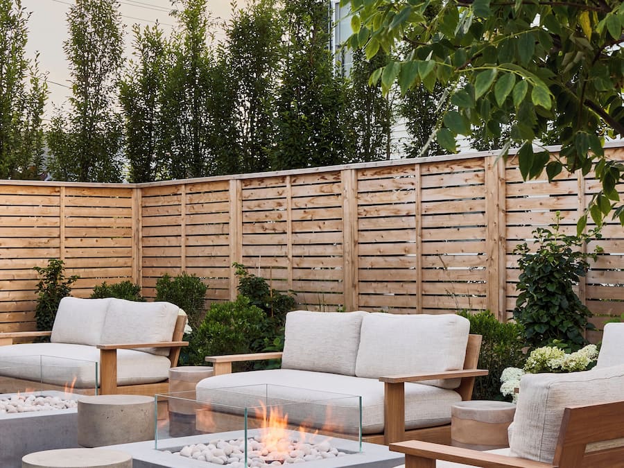 Un espace extérieur moderne aménagé avec des sièges, un foyer, des meubles en bois et une clôture en bois.