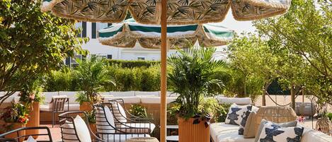 An outdoor seating area with a sofa, chairs, and a table under a striped umbrella.