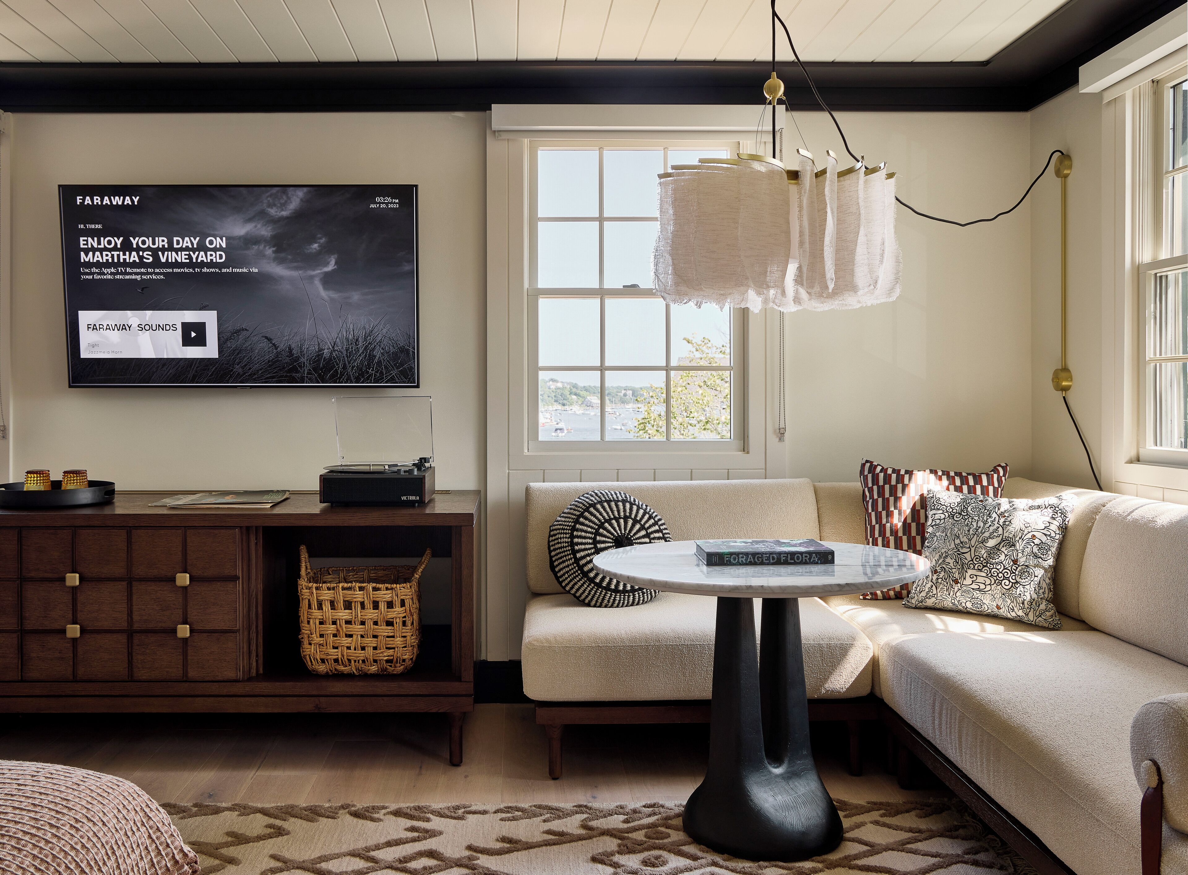 A cozy living room with a flat-screen TV, a record player, a woven basket, and a modern lamp.