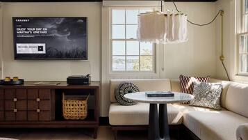 A cozy living room with a flat-screen TV, a record player, a woven basket, and a modern lamp.