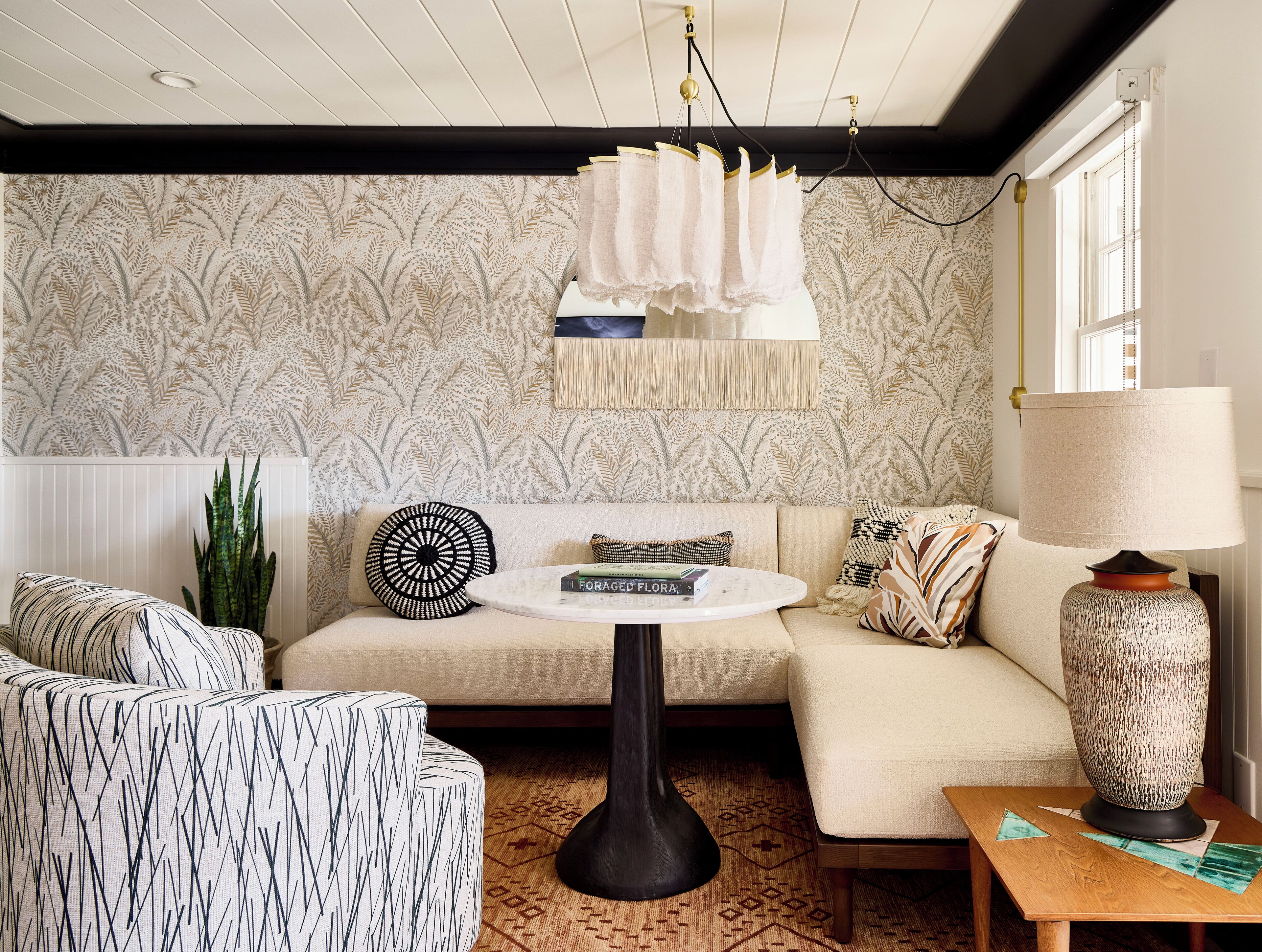 A living room with a sofa, a round coffee table, a patterned rug, and a large vase.