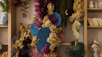 Une pièce comprenant une bibliothèque en bois, un comptoir d’accueil en marbre et divers objets décoratifs, notamment des plantes et des vases.