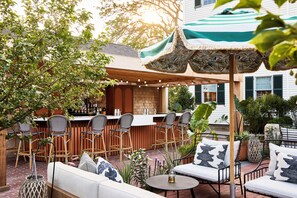 Relax on the patio with a sofa, chairs, and bar area, surrounded by lush potted plants.