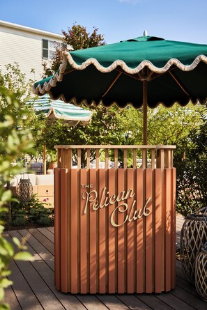 A wooden kiosk with the sign "The Pelican Club" on a wooden deck. - Faraway Martha's Vineyard (Edgartown)
