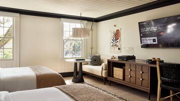 A hotel room with two beds, a sofa, a small table, a TV, and a fireplace.