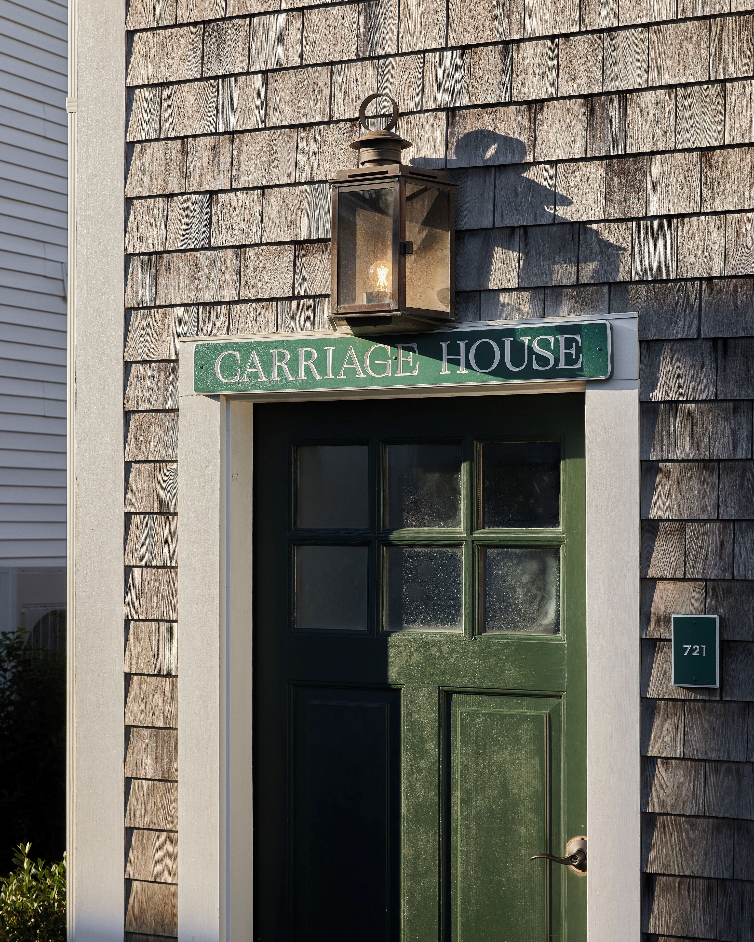 Una puerta verde con un letrero que dice "CARRIAGE HOUSE" en la parte superior y un letrero pequeño con el número "721" a la derecha.