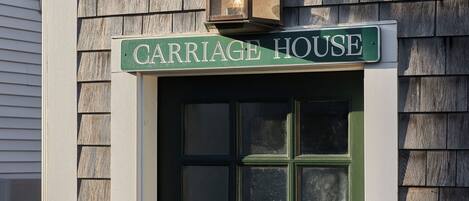 Una puerta verde con un letrero que dice "CARRIAGE HOUSE" en la parte superior y un letrero pequeño con el número "721" a la derecha.