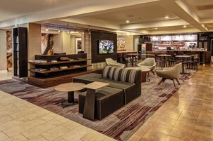 Un moderno vestíbulo de hotel con una zona de estar, un bar y una pantalla de televisión.