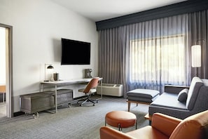 Une chambre d’hôtel équipée d’un bureau, d’une chaise, d’un canapé et d’un téléviseur fixé au mur.
