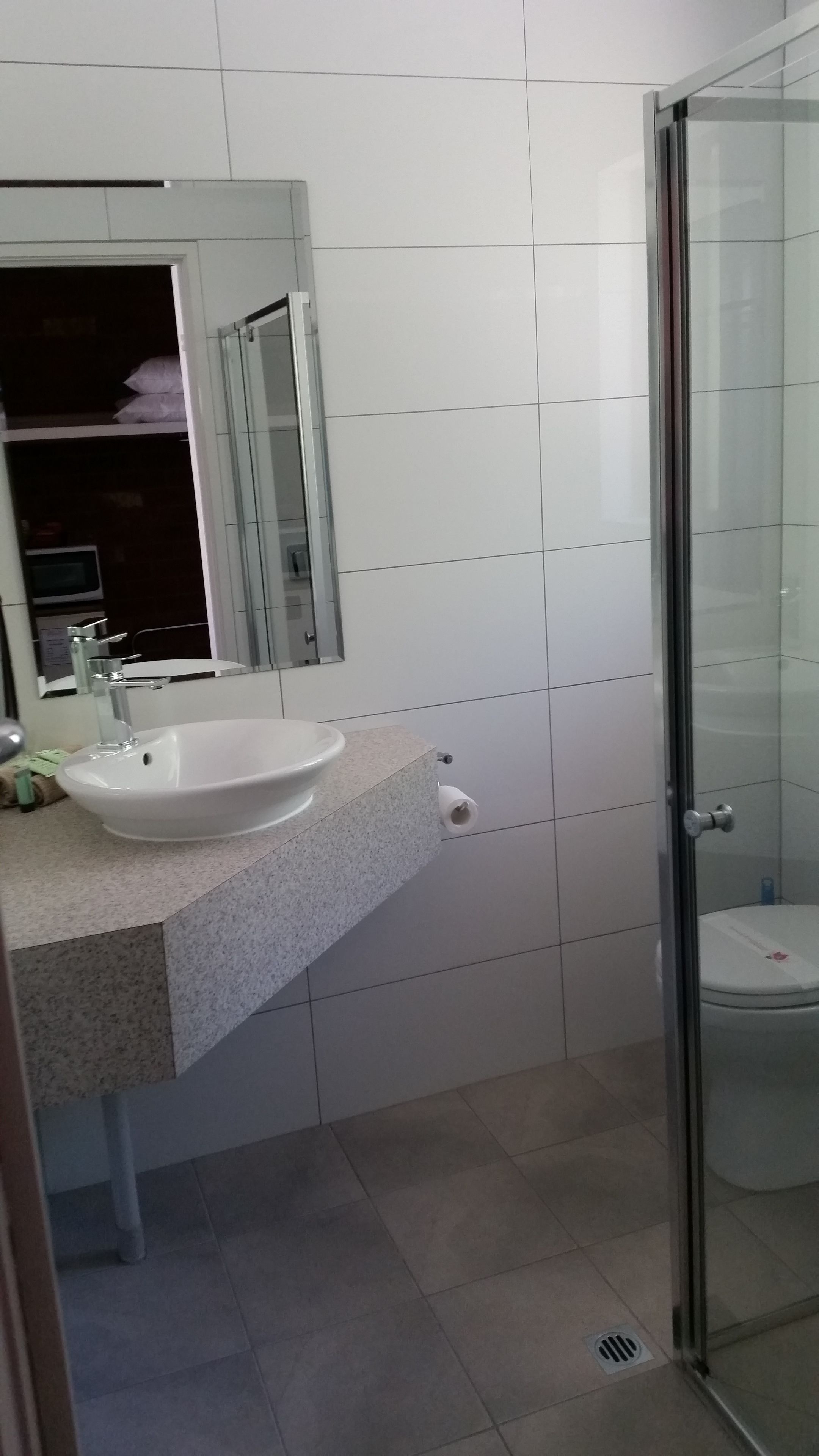 A bathroom with a sink, mirror, toilet, and shower.