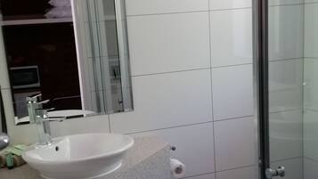 Un baño con lavamanos, espejo, inodoro y ducha.