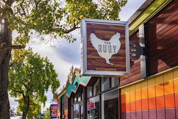 A restaurant sign with a chicken design, a neon 'OPEN' sign, and a colorful building facade.