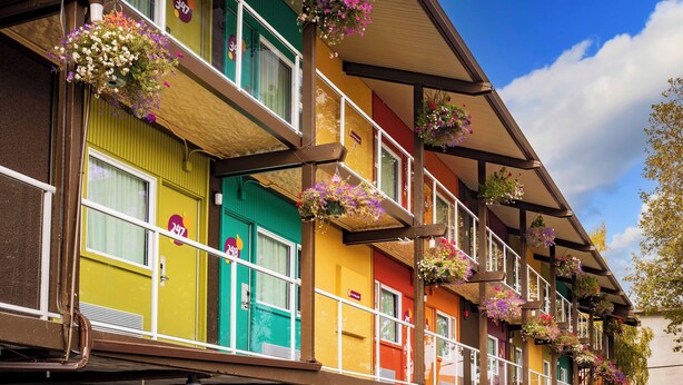 A row of colorful buildings with balconies, each adorned with hanging flower baskets. - Hotel Zed Victoria (Victoria)