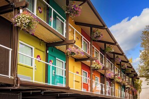 A row of colorful buildings with balconies, each adorned with hanging flower baskets.