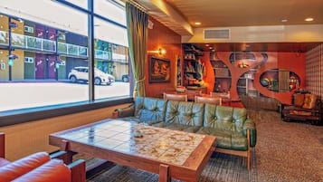 A hotel lobby with a green leather sofa, a wooden coffee table, and a view of the street outside.