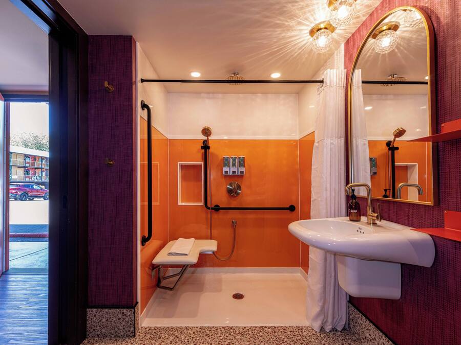 A modern bathroom with a walk-in shower, a white sink, and a large mirror.