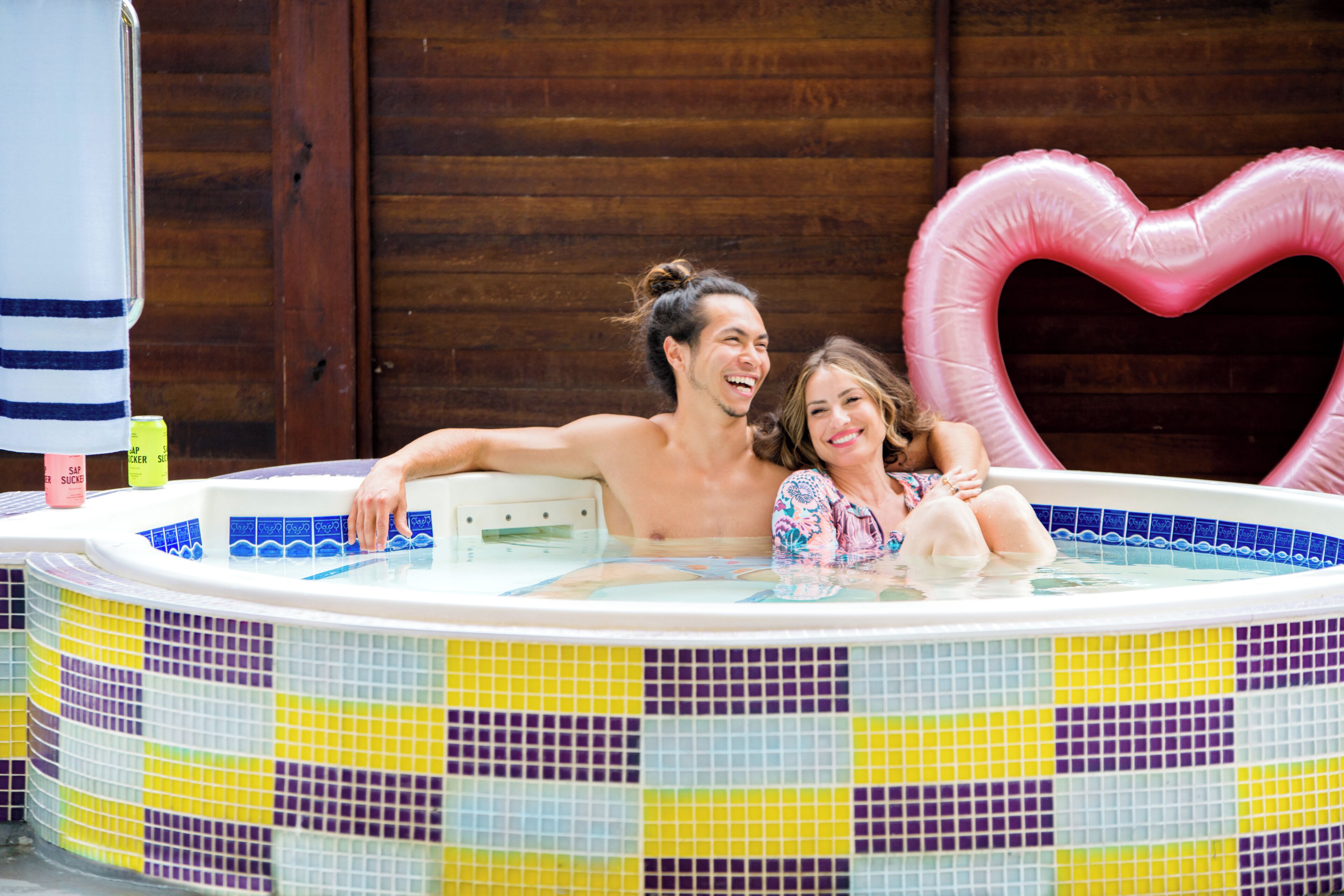 Un jacuzzi con mosaicos de colores y un adorno inflable con forma de corazón.