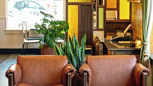 A lobby with a leather sofa, a potted plant, a desk with a typewriter, and a view of a car outside. - Hotel Zed Victoria (Victoria)