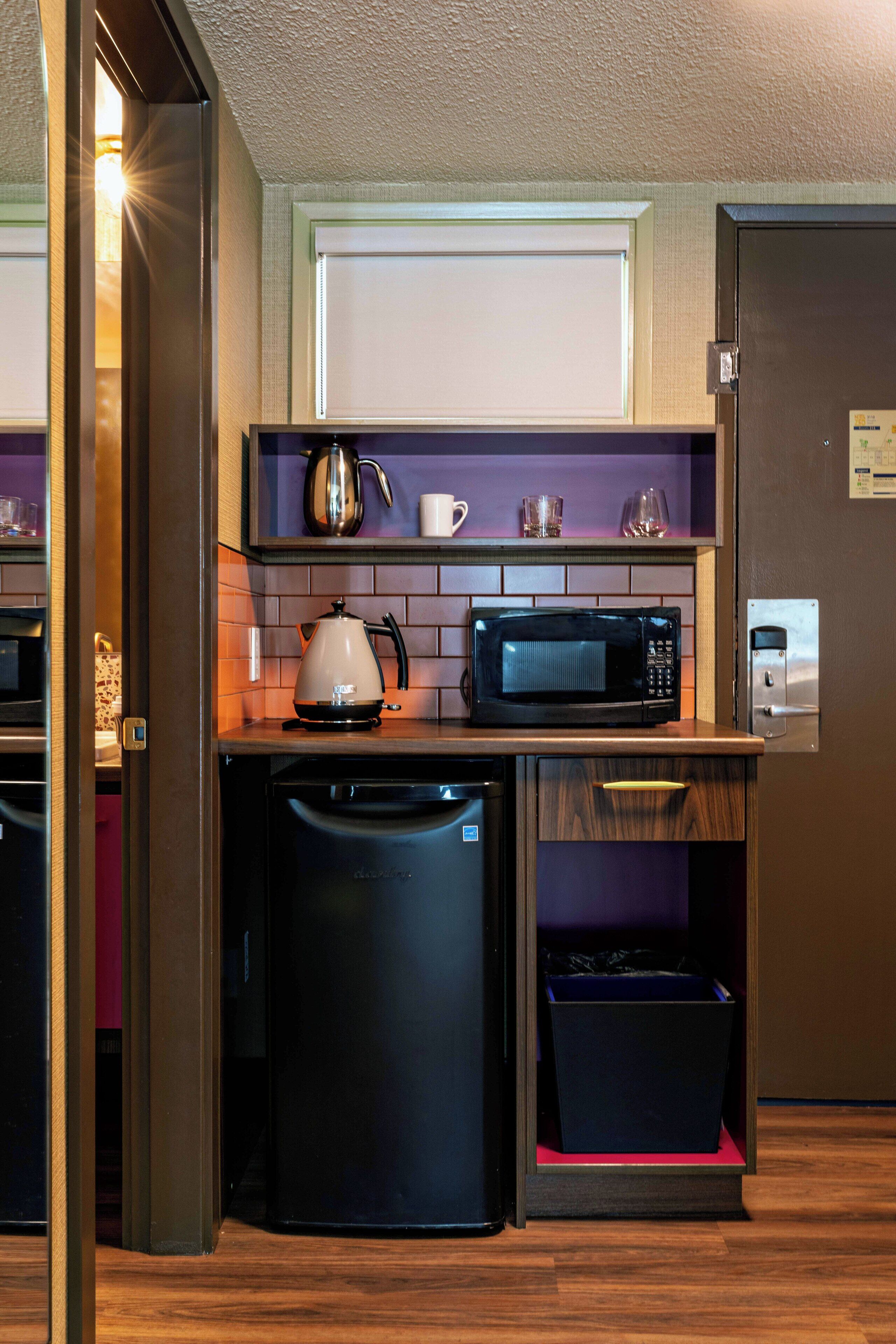 A compact kitchen with a microwave, kettle, and a small refrigerator.