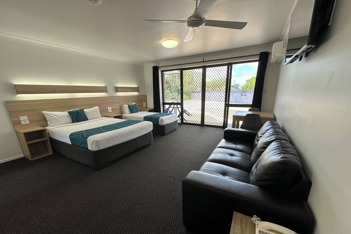 A hotel room with two beds, a sofa, a desk, and a phone.