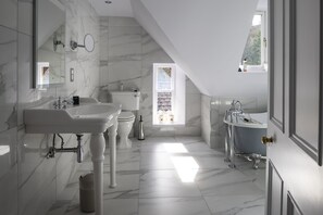 A modern bathroom with a white marble sink, a bathtub, and a toilet.