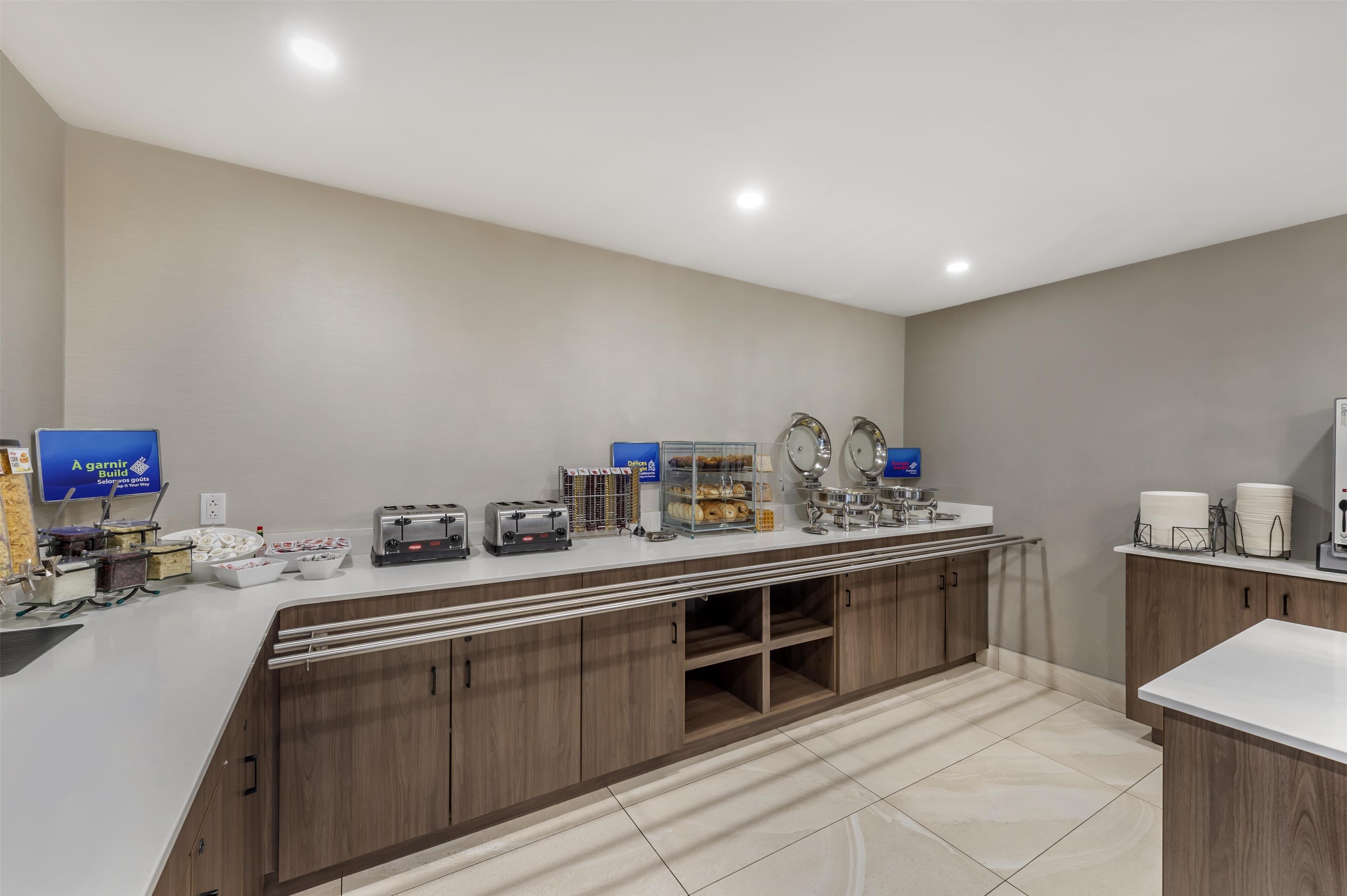 A modern kitchen with a white countertop, wooden cabinets, and various appliances like a toaster and coffee maker.