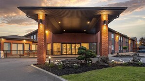 A modern hotel entrance with a covered walkway, brick facade, and landscaped garden. - Best Western Hotel Brossard (Brossard)