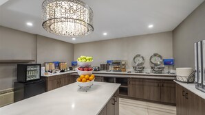 A modern kitchen with a central island, a refrigerator, and a decorative chandelier. - Best Western Hotel Brossard (Brossard)
