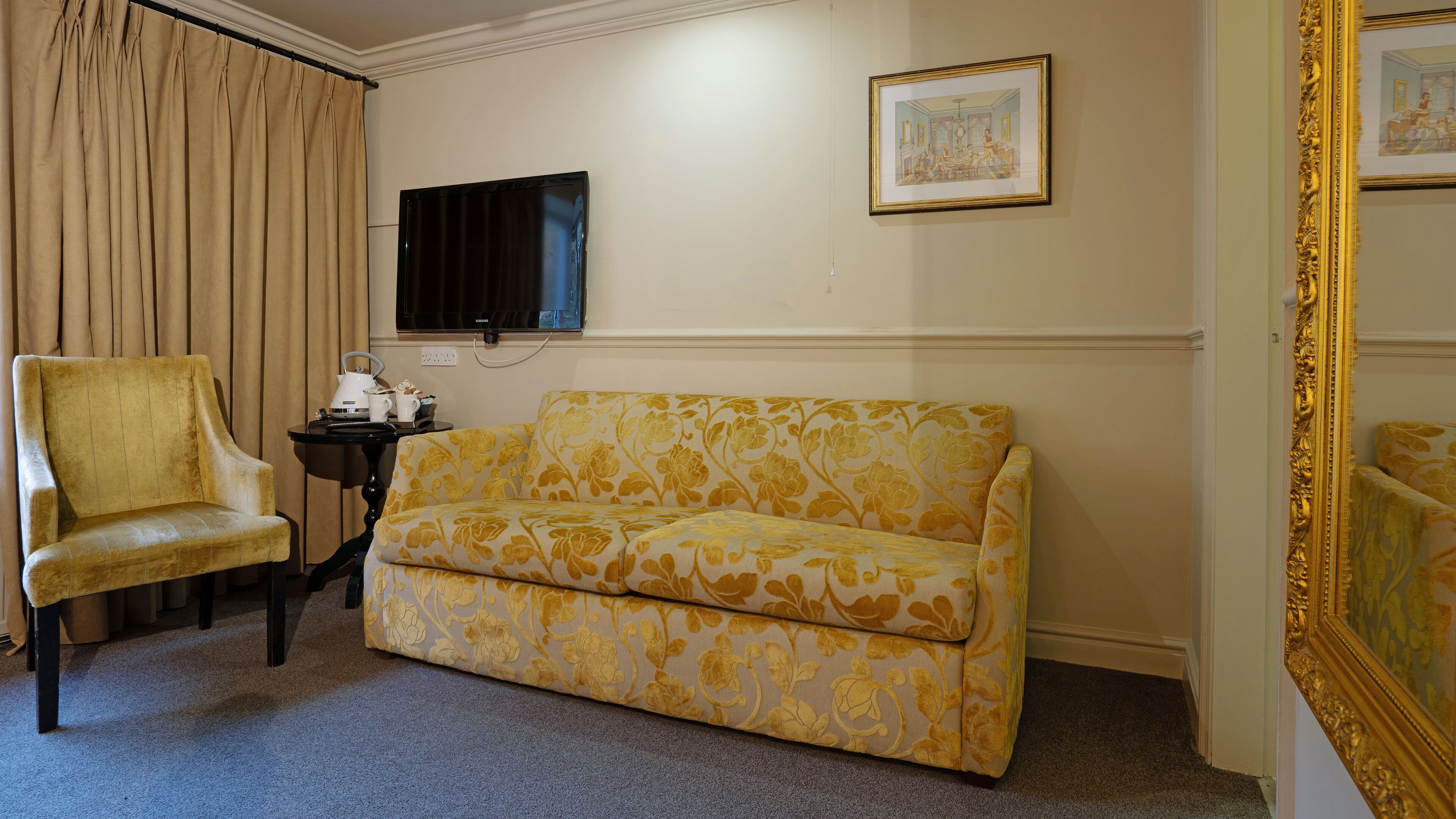 Une pièce comprenant un canapé, un fauteuil, un téléviseur et un tableau encadré accroché au mur.