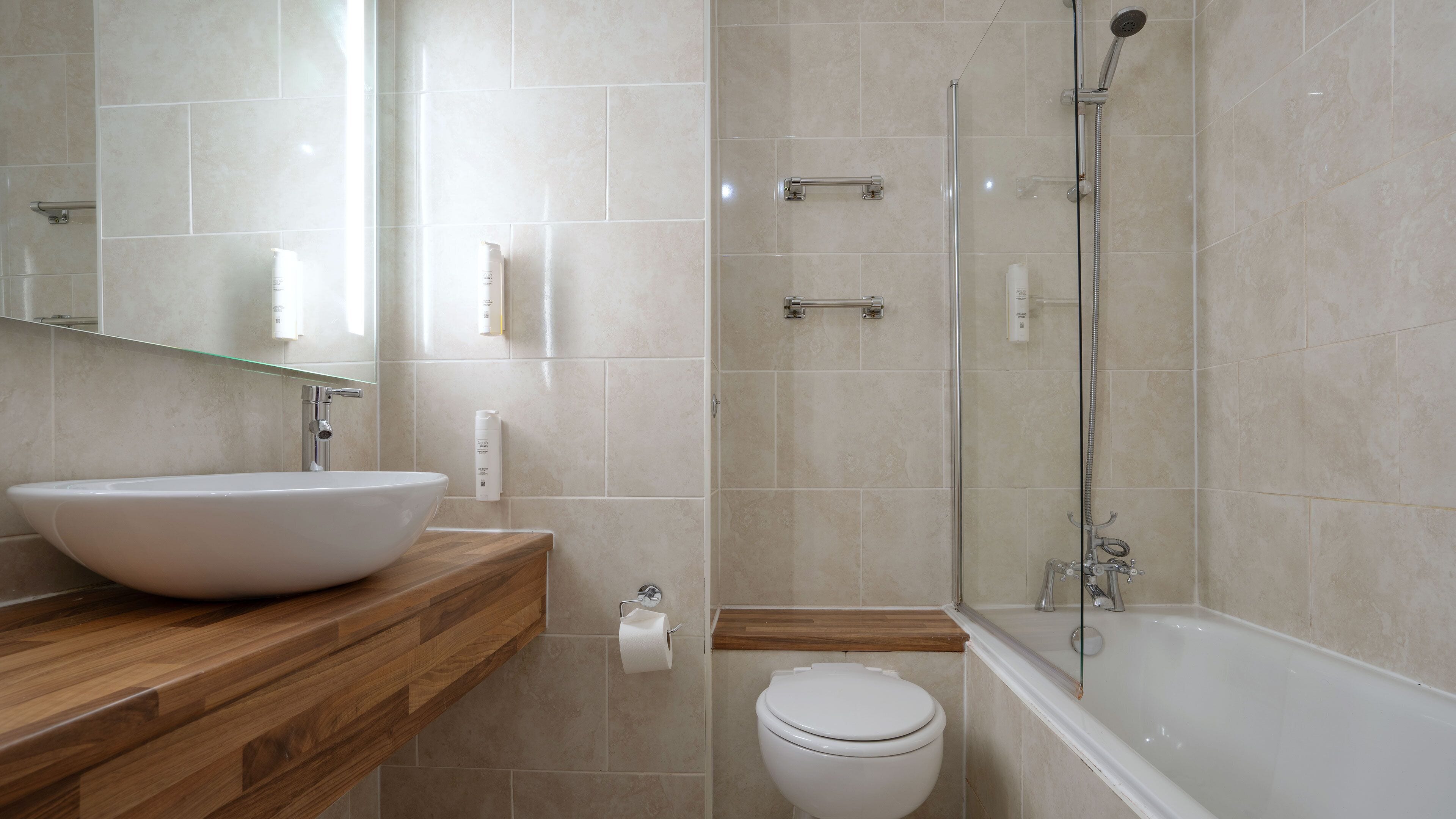 A bathroom with a large white sink, a toilet, and a glass-enclosed shower area.