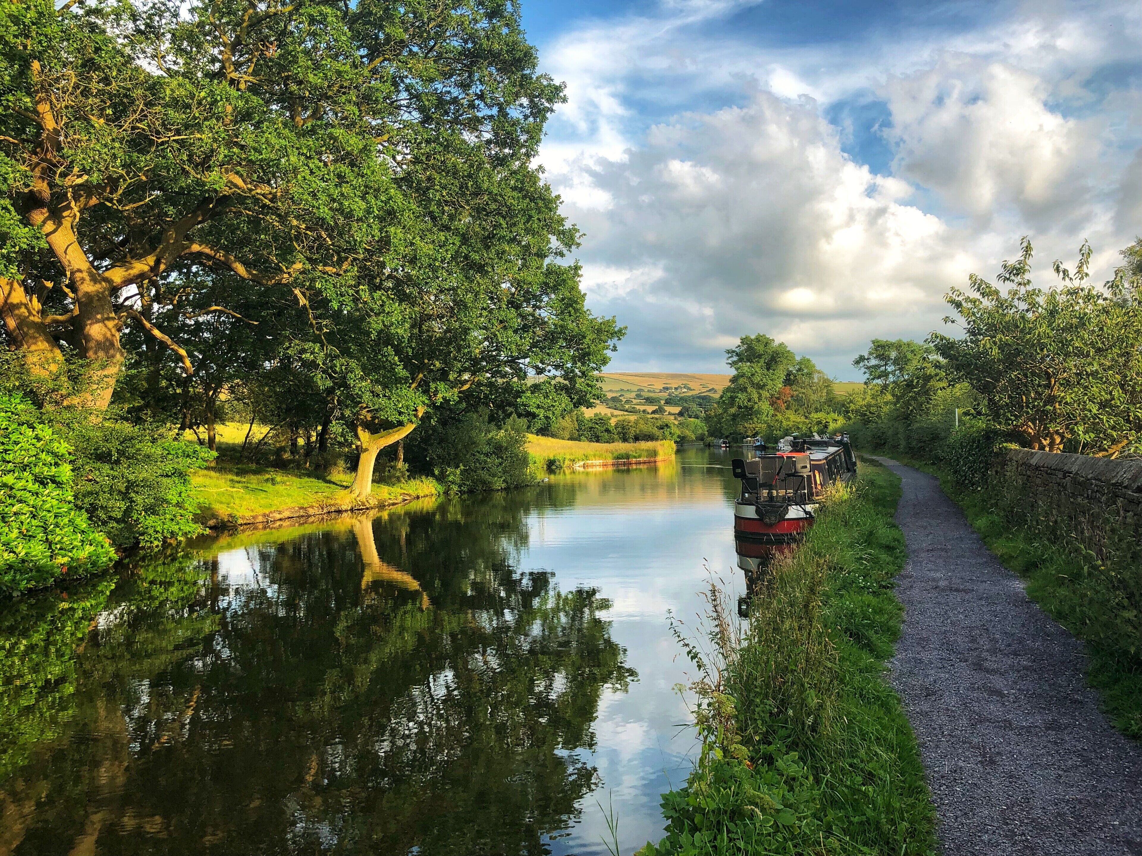A narrow waterway with a boat docked on the right, surrounded by lush greenery and trees.