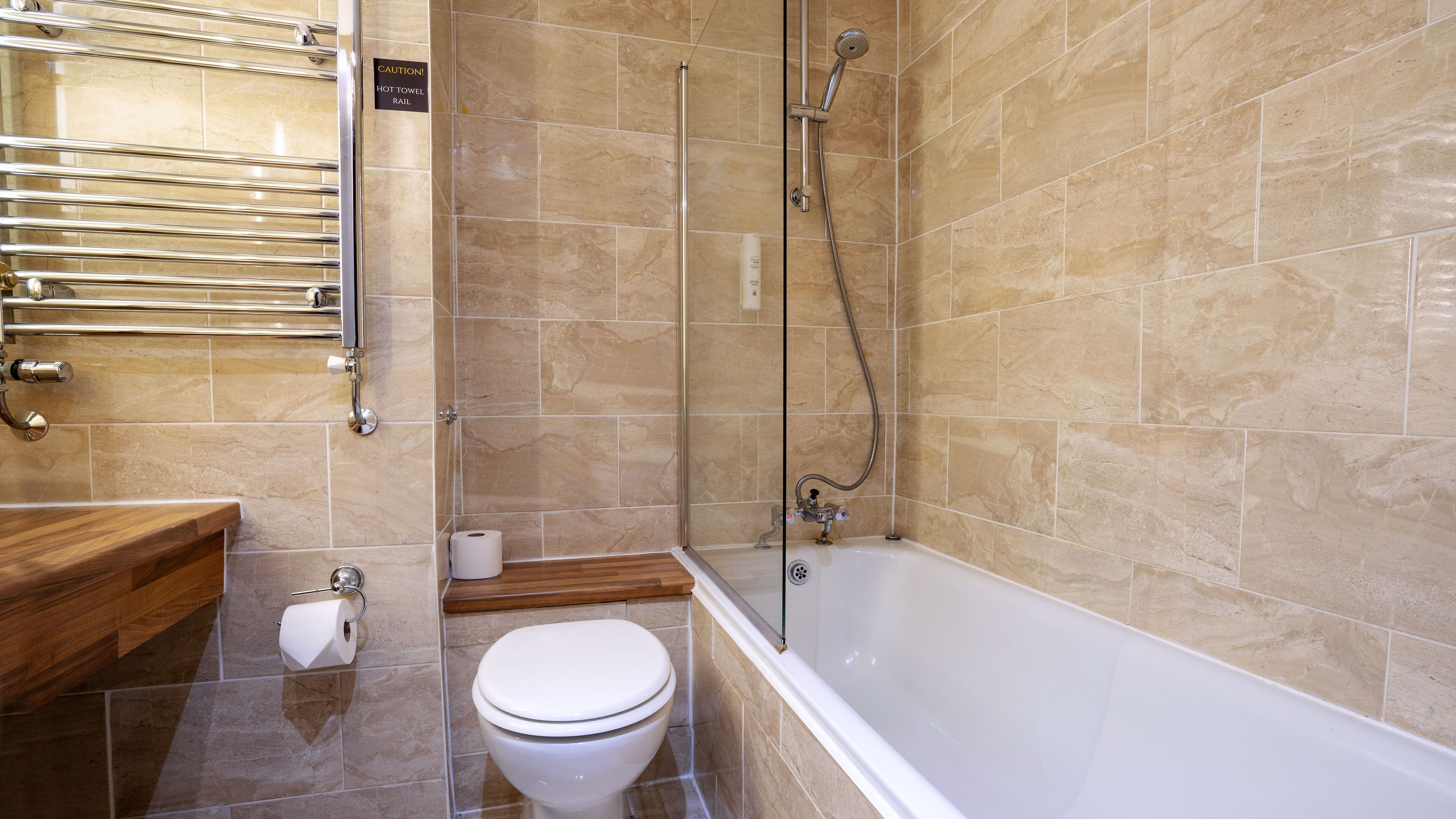 Un baño con bañera, inodoro y mampara de vidrio.