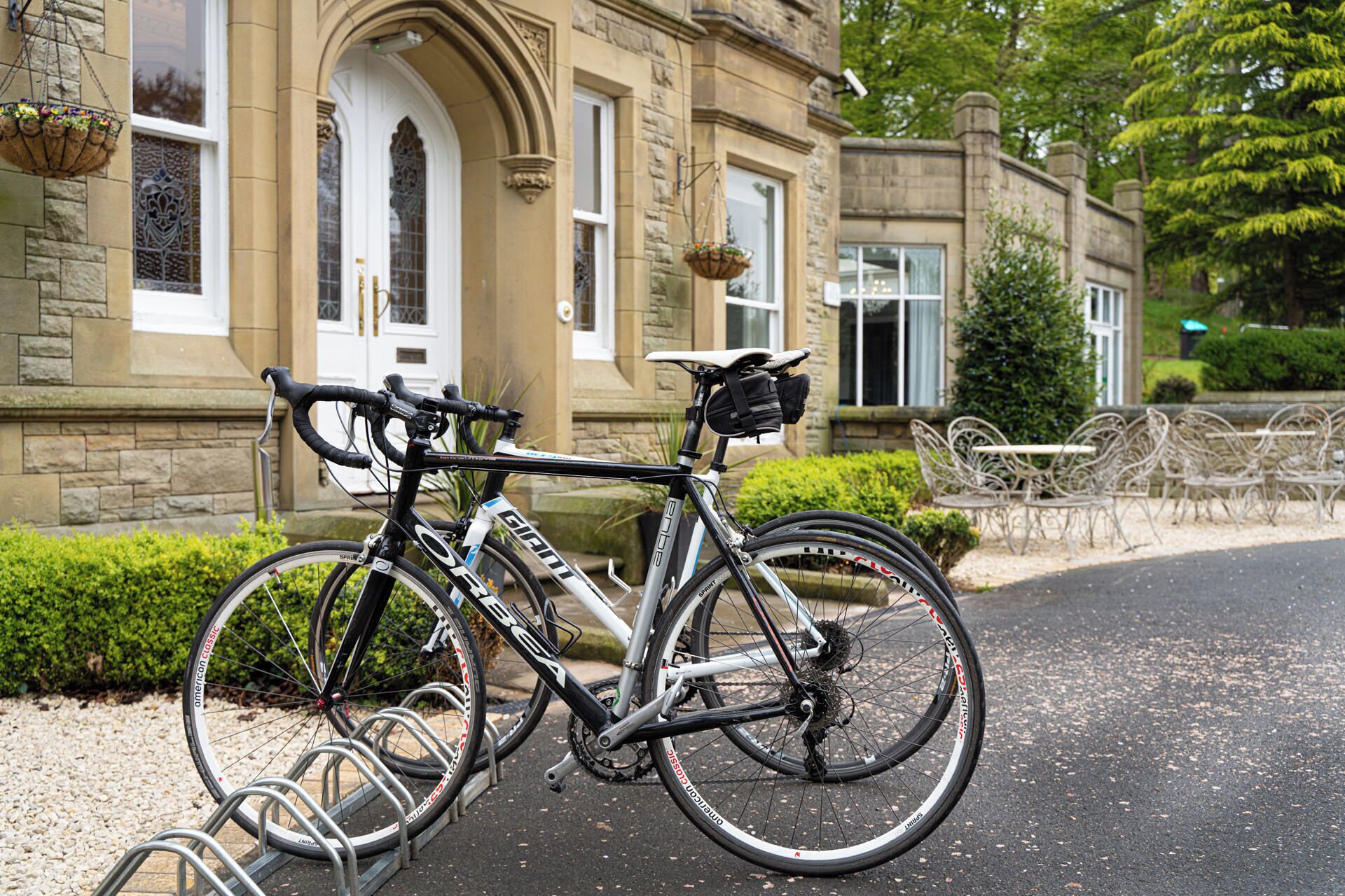 A bicycle parked in front of a stone building with a wrought iron gate and a bench area.