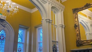 A room with a yellow wall, a chandelier, a red chair, a fireplace, and a mirror. - Hollin House Hotel (Macclesfield)