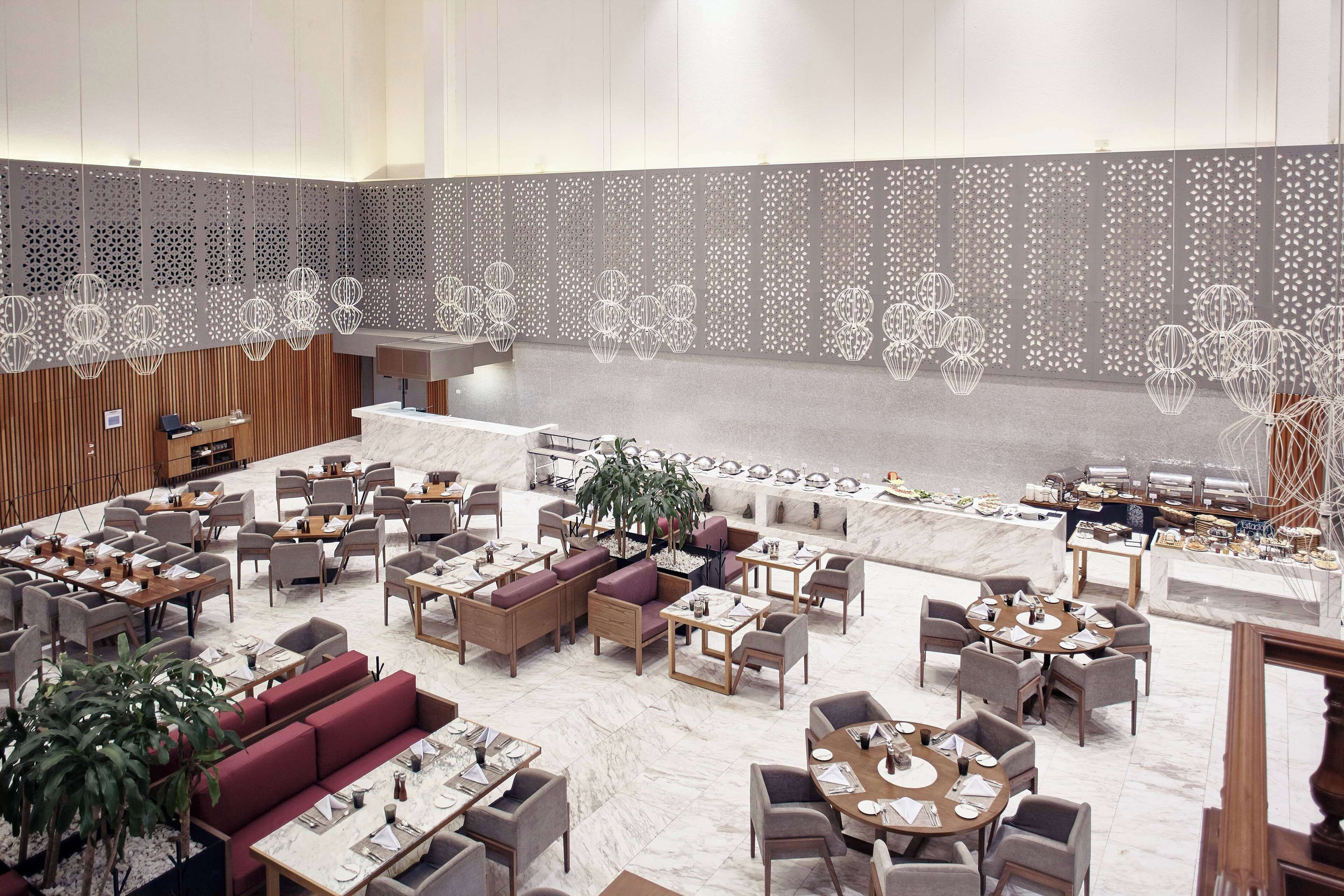 Un hall de hotel espacioso con varias zonas de estar, una recepción y un bufé.
