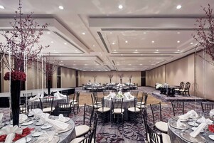 A banquet hall with round tables set for dining, chairs, and a carpeted floor.