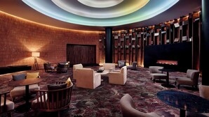 A modern lobby with a circular ceiling design, a fireplace, and a variety of seating arrangements.
