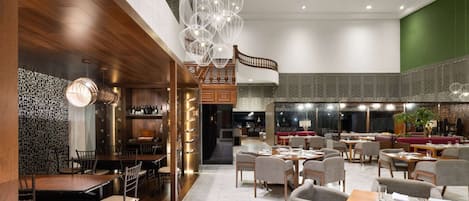 A spacious restaurant with high ceilings, a stained glass ceiling, and a mix of dining areas.